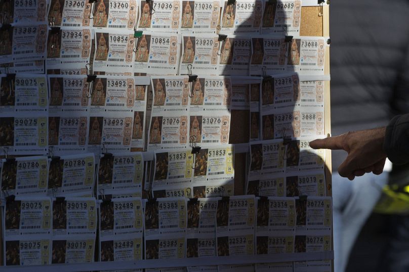 Mężczyzna wskazuje kupon na loterię bożonarodzeniową, który chce kupić na straganie w Madrycie.