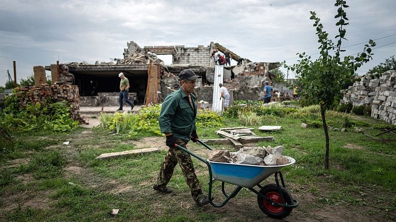 Wolontariusz wozi wózki ze śmieciami podczas sprzątania domu Żanny i Serhija Dynaevów, zniszczonego podczas rosyjskiego bombardowania, niedaleko Czernihowa.