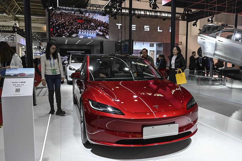 Ludzie wypróbowują elektryczny pojazd Tesli Model 3 na stoisku podczas China International Supply Chain Expo (CISCE) w Pekinie, 1 grudnia 2023 r. JADE GAO / AFP