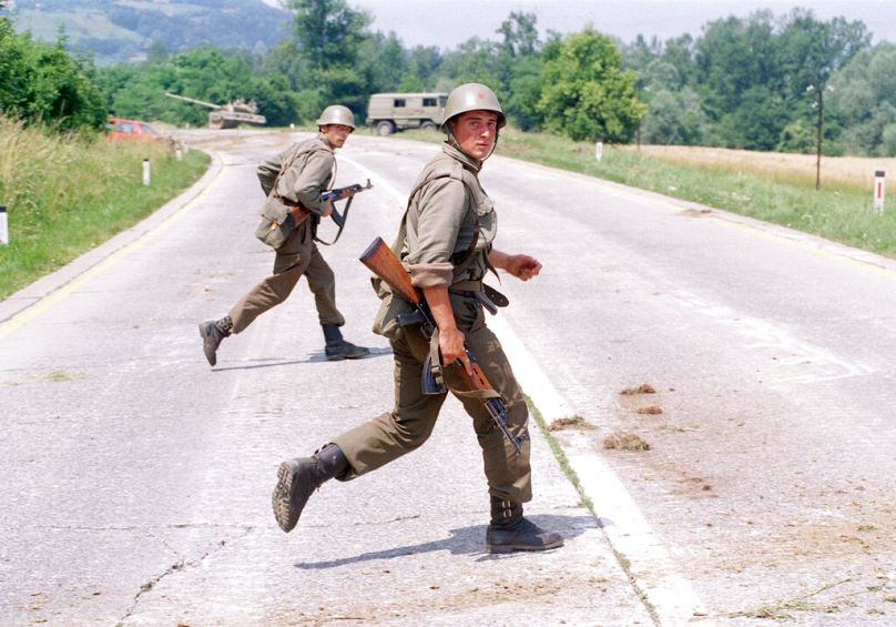 Dwóch jugosłowiańskich żołnierzy ukrywa się podczas strzelaniny z członkami słoweńskich sił obronnych w pobliżu Brezic, 25 mil od Zagrzebia, lipiec 1991 r.