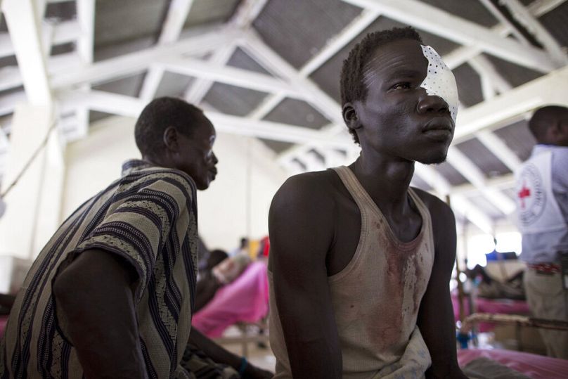 Mężczyzna siedzi na szpitalnym łóżku po leczeniu urazu oka w szpitalu Bor, stan Jonglei, Sudan Południowy, lipiec 2013 r.