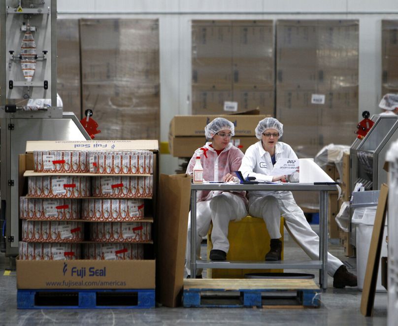 Dwóch pracowników pracuje w zakładzie produkującym koszulki, gdzie umieszczane są etykiety na pojemnikach w Chobani Greek Yogurt w South Edmeston, styczeń 2012