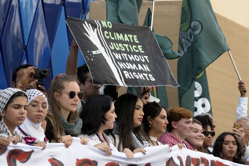 Propalestyńscy demonstranci biorący udział w proteście przeciwko wojnie między Izraelem a Hamasem trzymają tablicę na szczycie klimatycznym COP28 w Dubaju w Zjednoczonych Emiratach Arabskich.