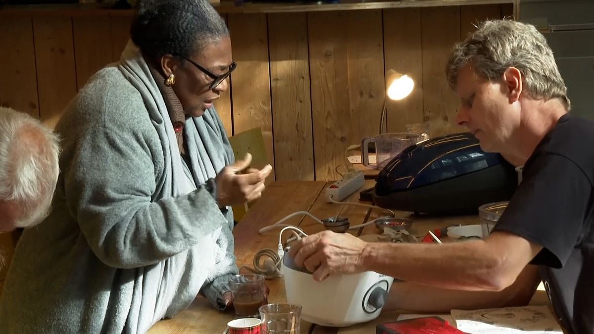 A fixer shows a woman how to repair her kitchen appliance