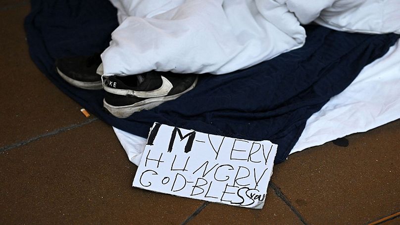 Czytanie znaku "Jestem bardzo głodny, Bóg zapłać" jest sfotografowane na końcu prowizorycznego łóżka i obozu dla szorstkiego śpiącego o świcie na Oxford Street w Londynie, 2 sierpnia 2023 r.