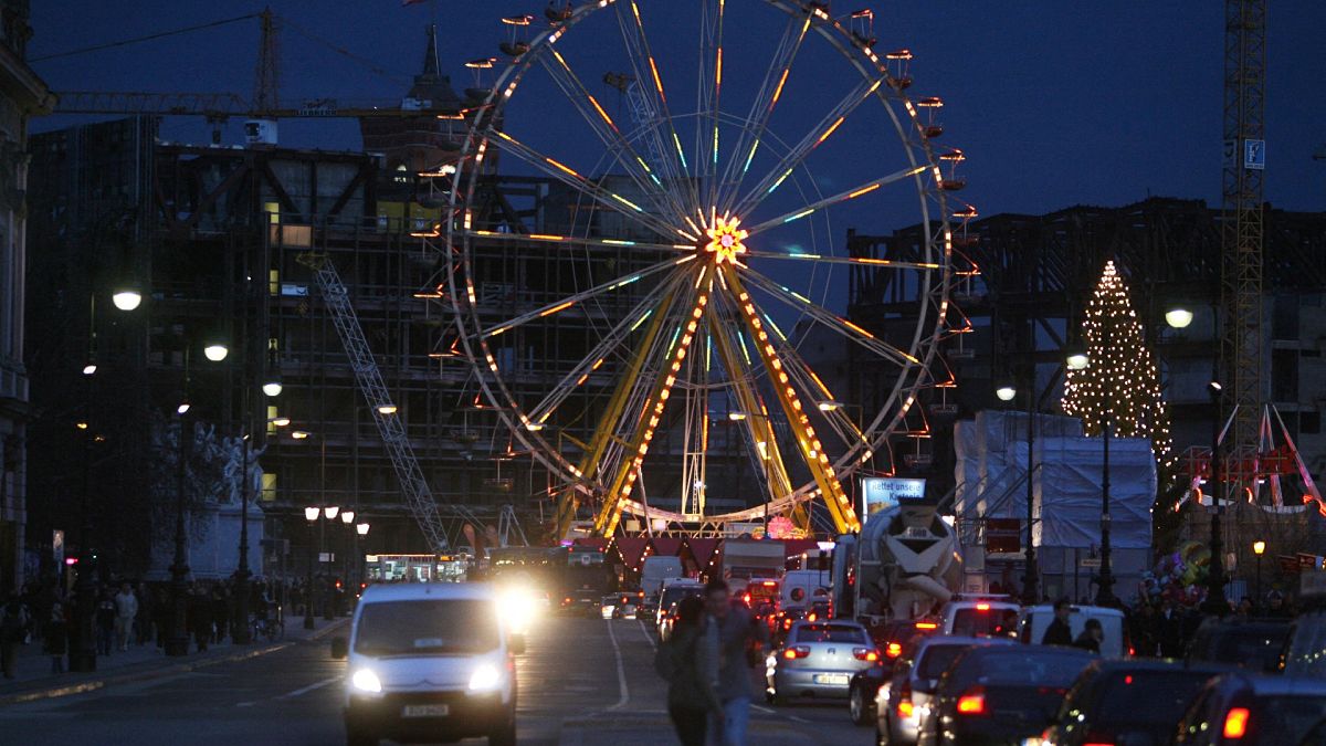 Traffic makes its way past a ferris wheel at one of the capital