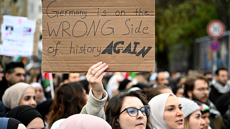 Demonstrant trzyma plakat z napisem „Niemcy znów stoją po złej stronie historii” podczas wiecu solidarności z Palestyńczykami na Oranienplatz w Berlinie