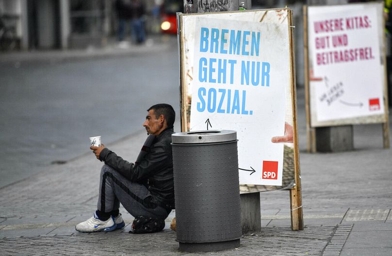 Mężczyzna błaga przed plakatem SPD z napisem „Brema działa tylko społecznie” w związku z wyborami regionalnymi w centrum Bremy, Niemcy, wtorek, 14 maja 2019 r.