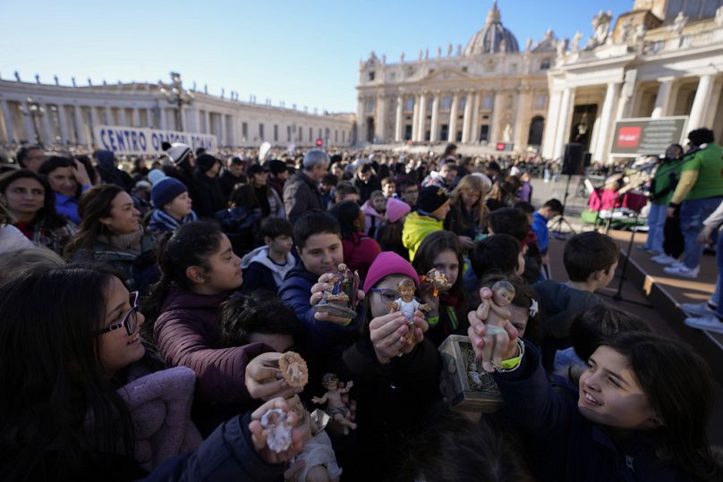 Dzieci trzymające figurki Dzieciątka Jezus czekają na południową modlitwę Anioł Pański papieża Franciszka