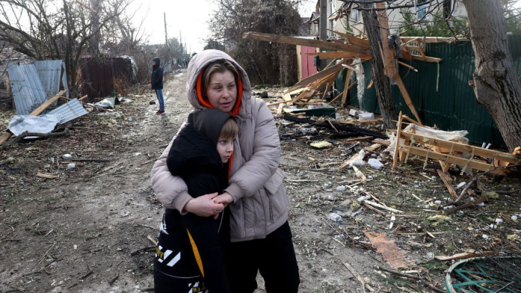 Local residents stand among debris on the street outside a house destroyed as a result of a drone attack in Tairove, Odesa region on Sunday