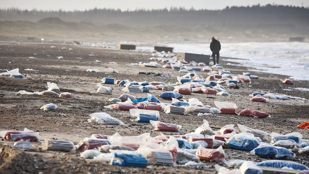 A person walks past stranded containers in the area between Tranum and Slette beach, in Denmark, Saturday, Dec. 23, 2023