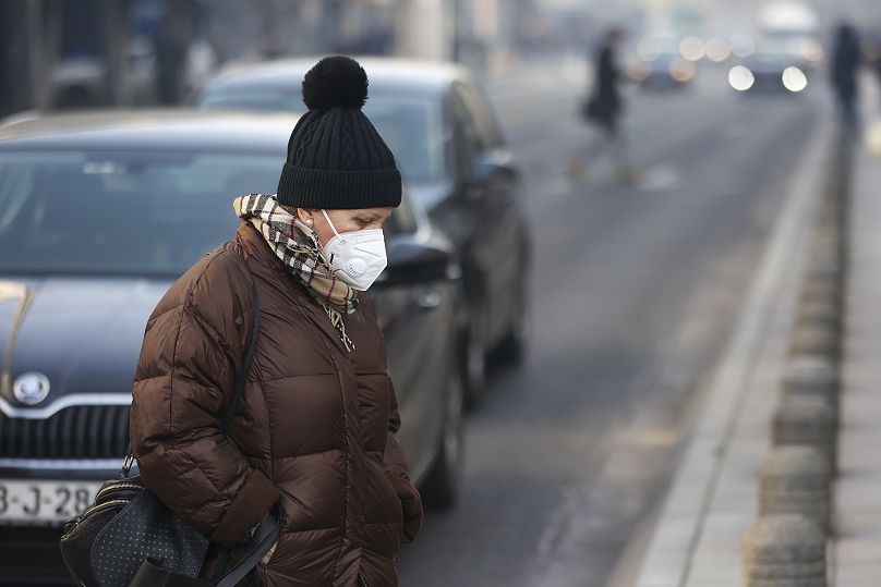 Kobieta nosi maskę spowitą mgłą zanieczyszczeń, gdy smog spowija Sarajewo, Bośnia, środa, 20 grudnia 2023 r.