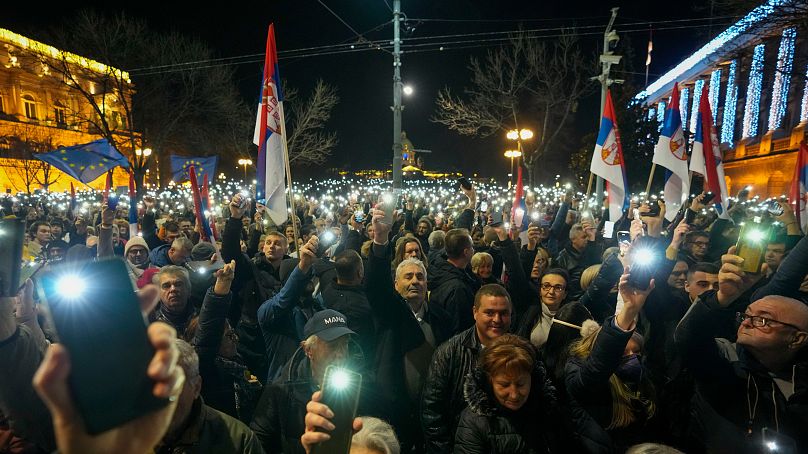 Zwolennicy serbskiej opozycji trzymają światła podczas protestu przed budynkiem komisji wyborczej w Belgradzie