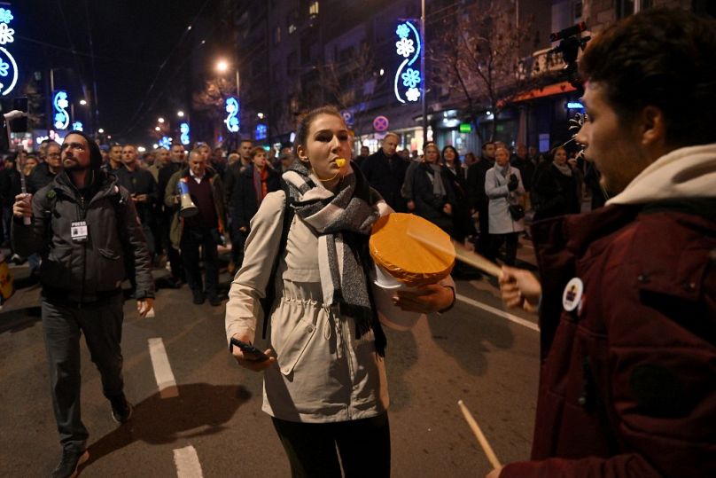 Demonstrant gwiżdże, gdy zwolennicy opozycji biorą udział w marszu podczas protestu w Belgradzie, 25 grudnia 2023 r., tydzień po wyborach powszechnych.