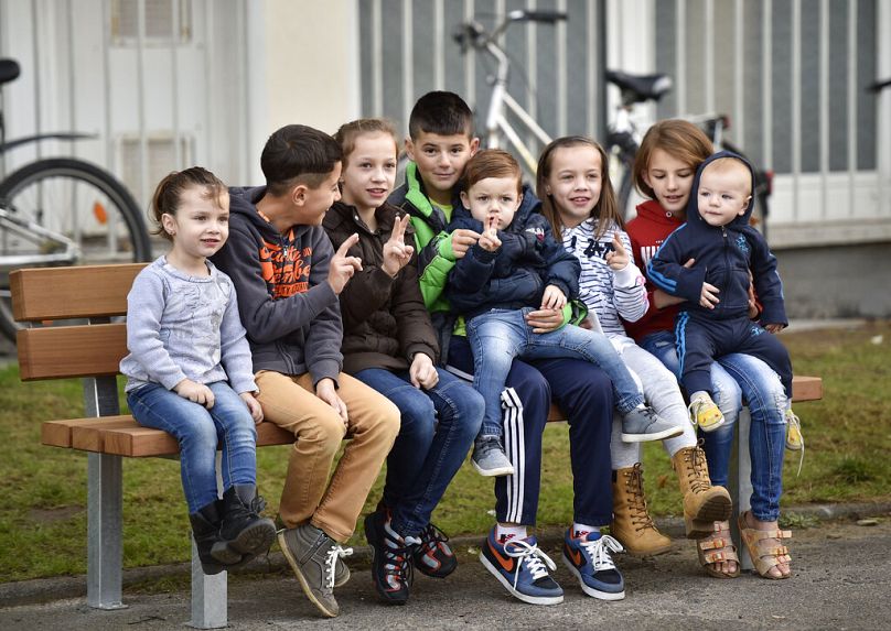 Dzieci-migranci siedzą na ławce i migają znakiem zwycięstwa, czekając na wizytę prezydenta Niemiec Joachima Gaucka w Bergisch Gladbach w zachodnich Niemczech.