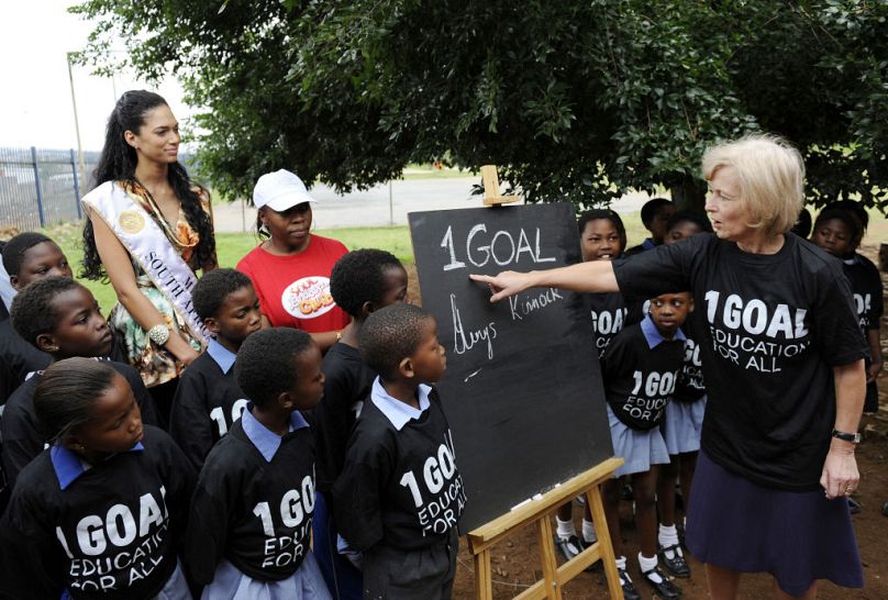 Baronowa Glenys Kinnock (po prawej) i Miss Republiki Południowej Afryki 2008 Tatum Keshwar (po lewej) pozują z uczniami szkoły w Soweto w ramach kampanii 1GOAL w 2009 r.