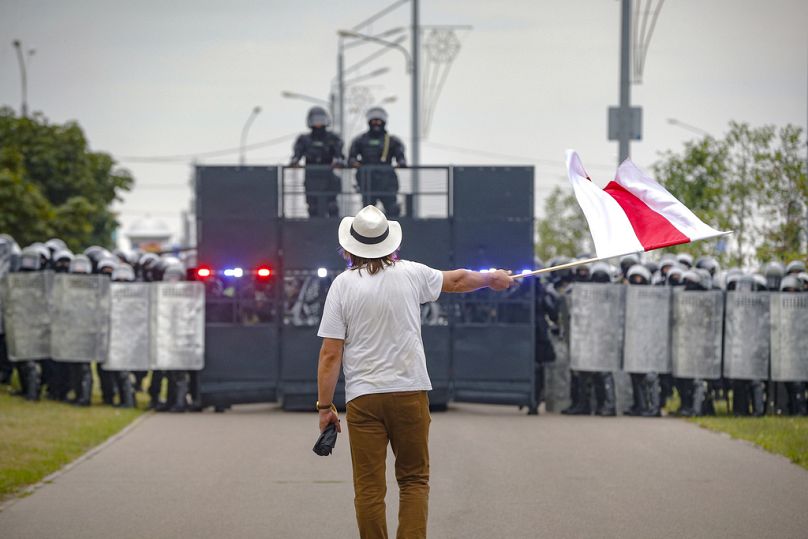 Artysta Aleś Puszkin, który zmarł w lipcu podczas pobytu w więzieniu na Białorusi za przestrzeganie praw człowieka, macha czerwono-białą flagą symbolizującą sprzeciw wobec Łukaszenki w 2020 r.