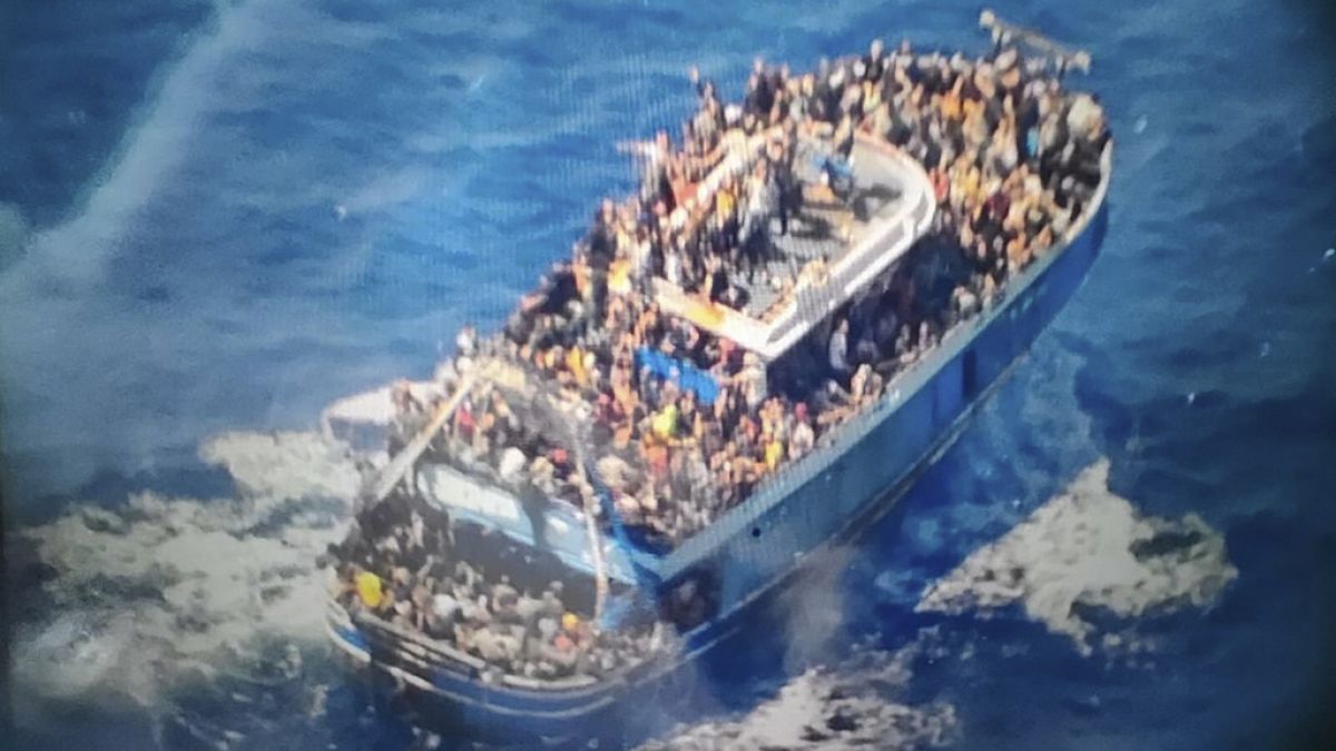 scores of people sit on a battered fishing boat that later capsized and sank off southern Greece.