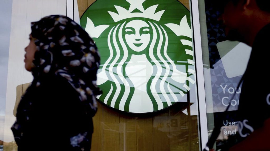 FILE - A woman walks past a Starbucks Coffee shop in Kuala Lumpur, Malaysia in July 2017