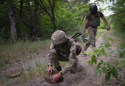 Ukraińscy żołnierze podkładają miny przeciwpancerne na leśnej drodze na potencjalnej drodze wojsk rosyjskich w obwodzie donieckim na Ukrainie, czerwiec 2022 r.