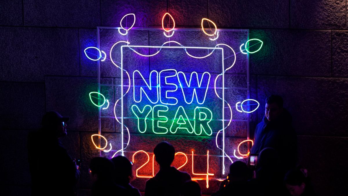 Visitors pose for a photo in front of an illuminated decoration on New Year