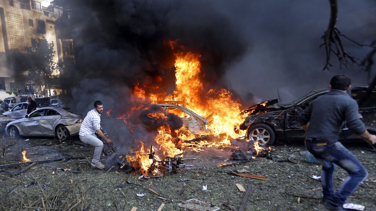 People stay next to an injured man after an explosion in Kerman, Iran.