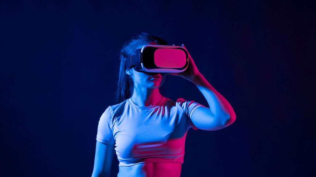 Young woman wearing a virtual reality headset goggles and playing a game in metaverse.