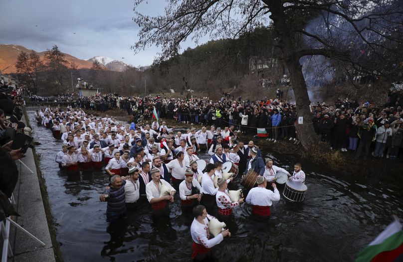 Mężczyźni grają na dudach i bębnach, brodząc do zimnej rzeki Tundzha, aby uczcić Święto Trzech Króli, w mieście Kalofer w Bułgarii, sobota, 6 stycznia 2024 r.