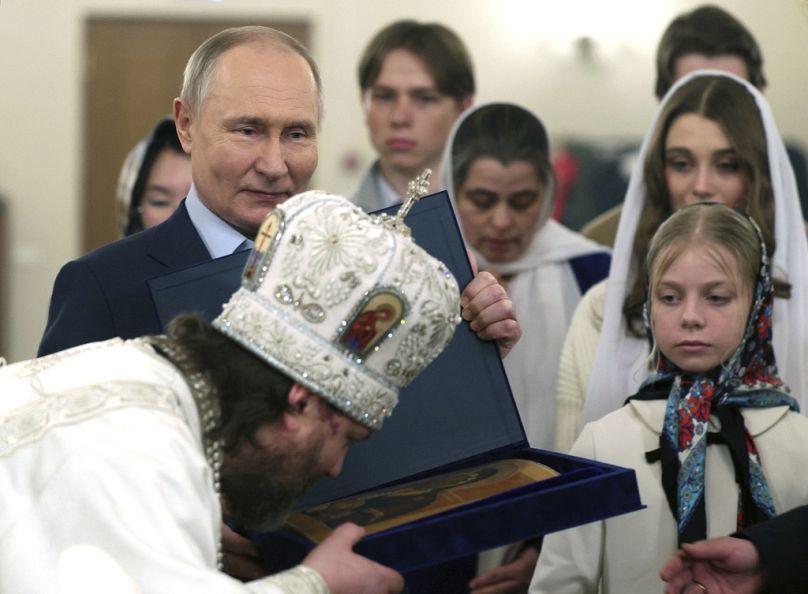 Rosyjski prawosławny arcybiskup Odintsowa i Krasnogorska Foma (Nikołaj Mosołow), na pierwszym planie, całuje ikonę, gdy w pobliżu stoi prezydent Rosji Władimir Putin (po lewej).