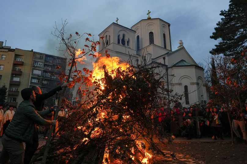 Ludzie palą suszone gałęzie dębu, symbol kłody Bożego Narodzenia podczas prawosławnej Wigilii, przed kościołem św. Sawy w Belgradzie w Serbii.