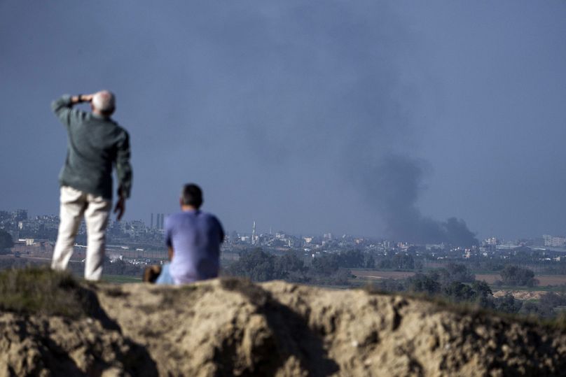 Ludzie obserwują dym unoszący się w niebo po eksplozji w Strefie Gazy, widziany z południowego Izraela, sobota, 6 stycznia 2024 r.