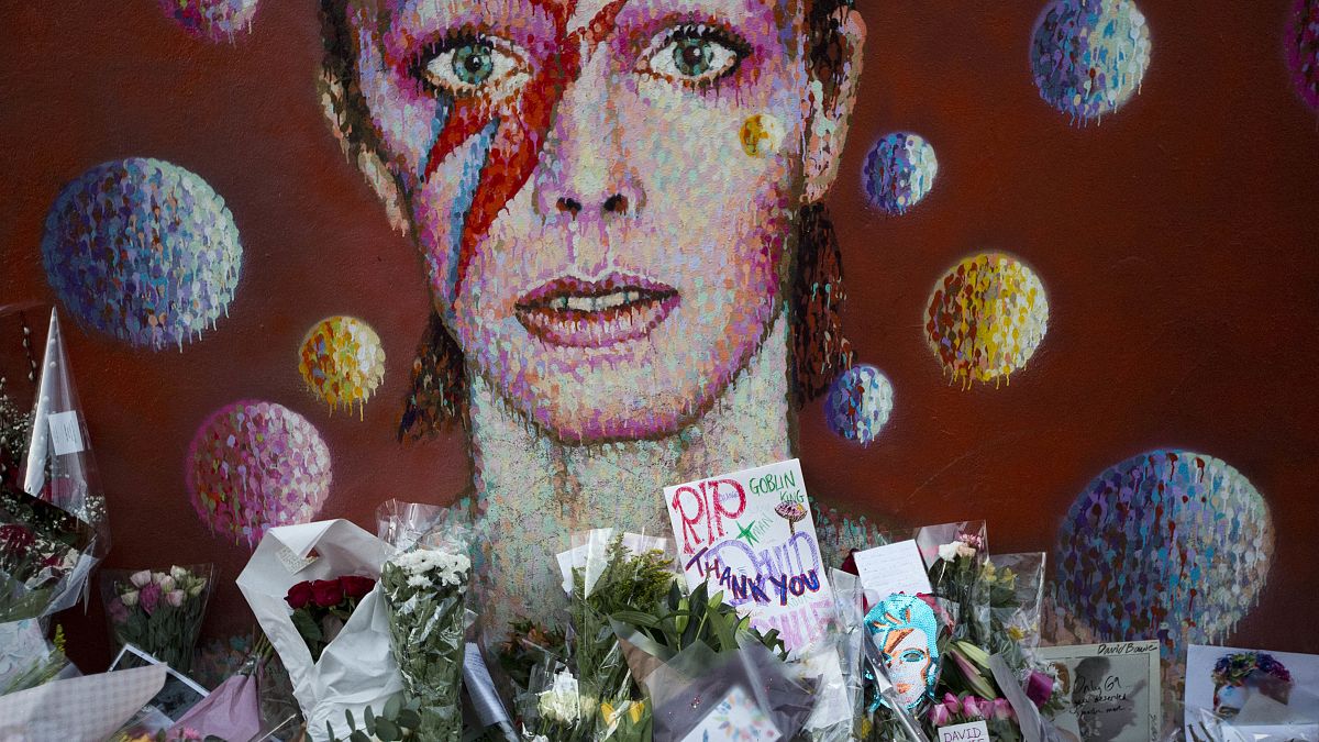 Tributes lie beneath a mural of singer David Bowie by artist Jimmy C in Brixton, south London.