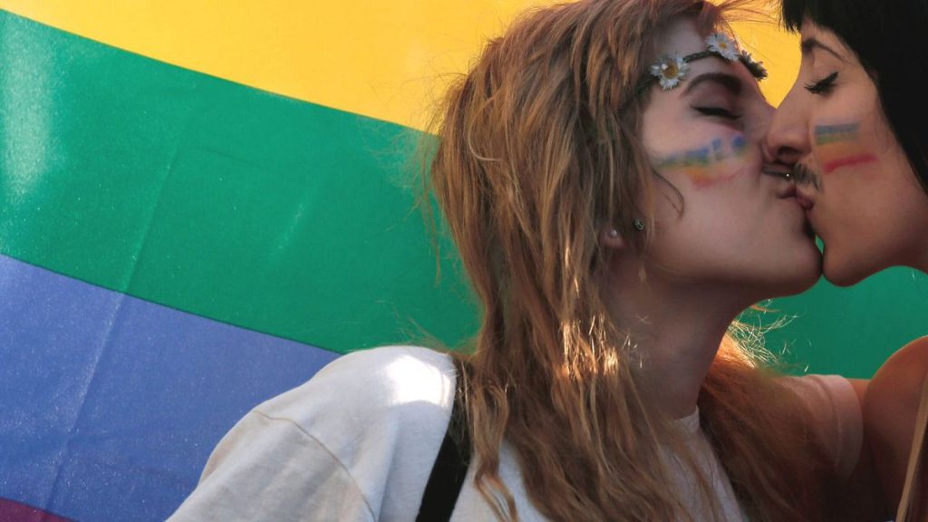 In this June 14, 2014 file photo, two women kiss in front of a rainbow flag in central Athens.