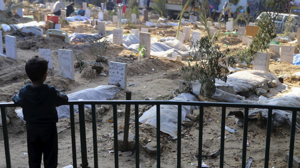 A Palestinian child looks at the graves of people killed in the Israeli bombardment of the Gaza Strip and buried inside the Shifa Hospital grounds in Gaza City in December