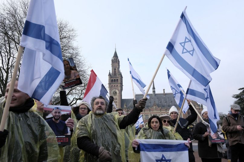 Protestujący machają izraelskimi flagami i trzymają zdjęcia zakładników porwanych przez Hamas podczas demonstracji przed Międzynarodowym Trybunałem Sprawiedliwości w Hadze w czwartek