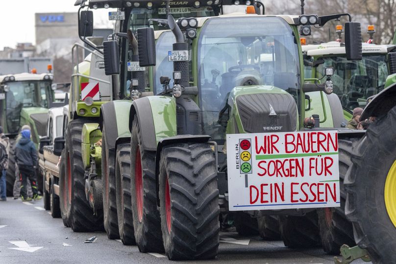 Znak w języku niemieckim "My, rolnicy, dbamy o Twoją żywność" wisi na traktorze zaparkowanym przy Bismarckstraße podczas protestu rolników w Berlinie, 15 stycznia 2024 r.