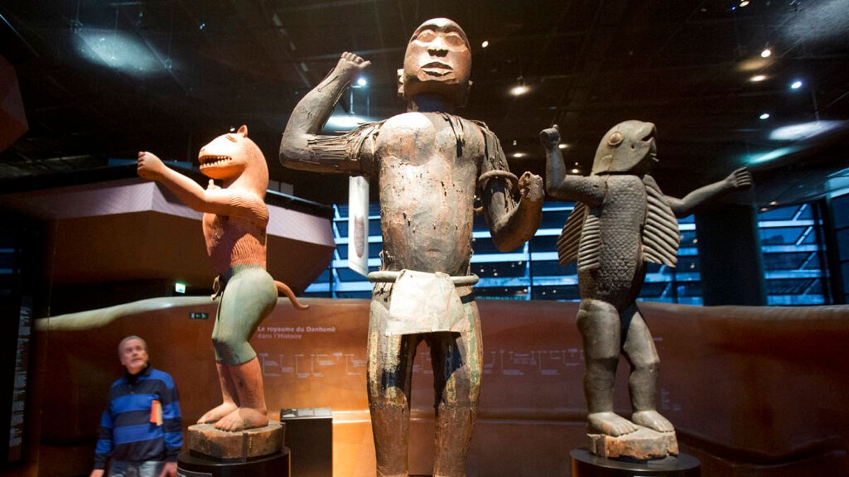 A visitor looks at wooden royal statues of the Dahomey kingdom in present-day Benin, dated 19th century, at the Quai Branly museum in Paris in 2018.