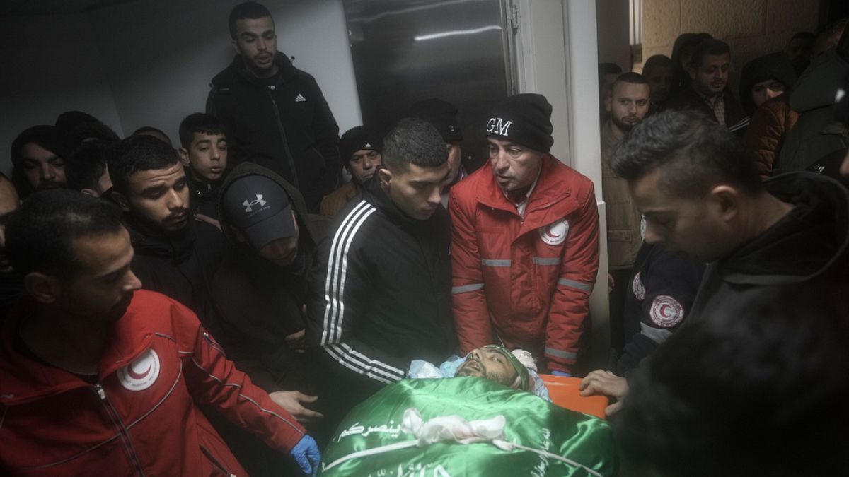 Palestinians gather around the body of Muhammad Jalamneh, draped in the Hamas militant group flag, in the morgue of Ibn Sina Hospital after he was killed.