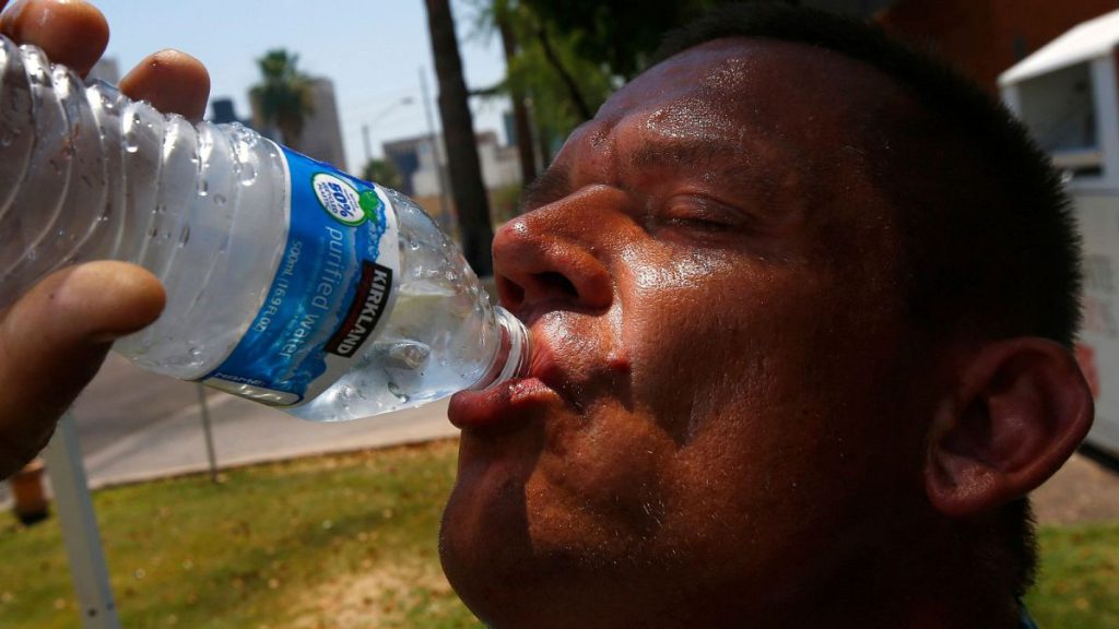A man takes a drink of water as he tries to keep hydrated and cool as temperatures climb to near-record highs in Phoenix, US, 2017.