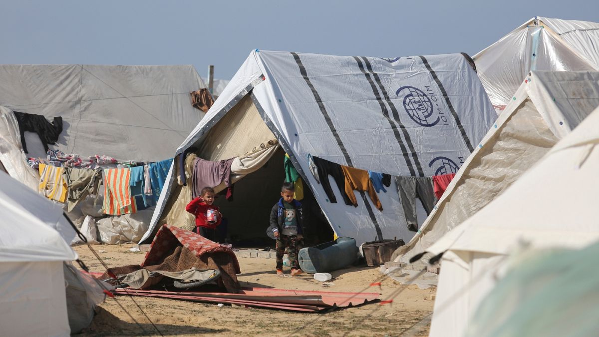 Palestinian children displaced by Israeli air and ground offensive on the Gaza Strip walk through a temporary tent camp near Kerem Shalom crossing in Rafah, Sunday, Jan. 14, 2