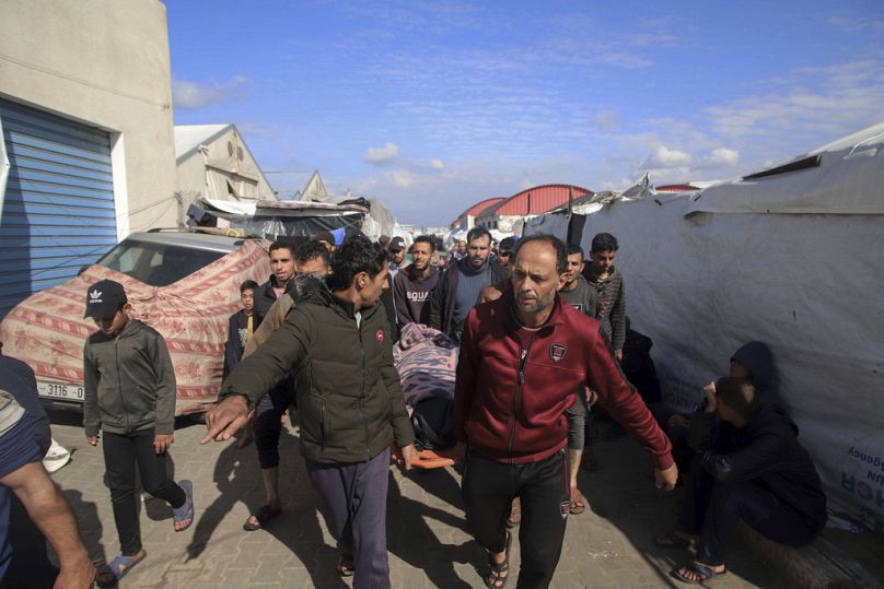 Palestyńczycy niosą ciało osoby zabitej podczas izraelskiego bombardowania w budynku ośrodka szkolenia zawodowego UNRWA, który służy jako schronienie dla wysiedleńców.