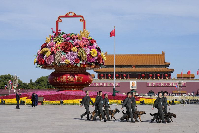 Funkcjonariusze bezpieczeństwa spacerują z psami po placu Tiananmen podczas ceremonii otwarcia Forum Pasa i Szlaku w Pekinie, październik 2023 r.