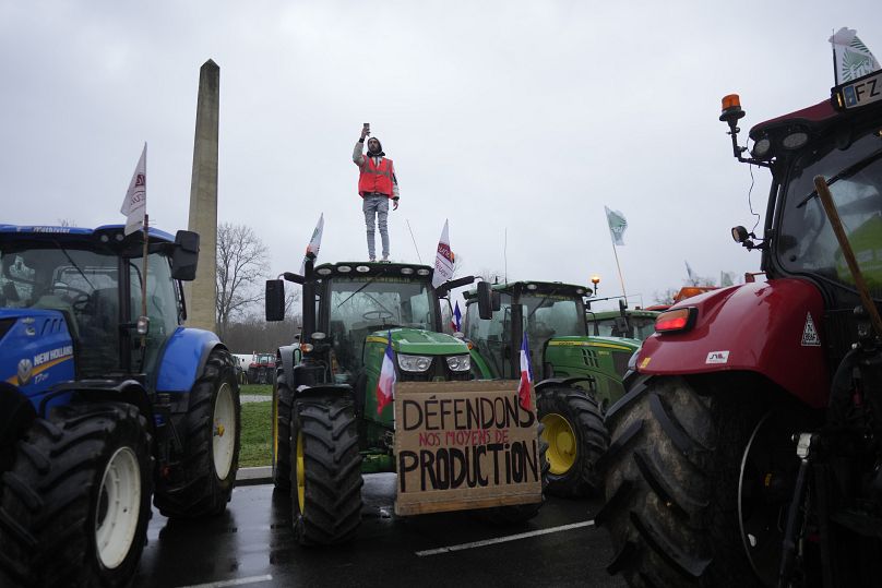 Rolnik stoi na traktorze, gdy rolnicy blokują rondo w Fontainebleau na południe od Paryża.