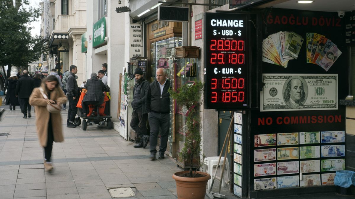 Peple walk next to an exchange currency shop in Istanbul, Turkey, Thursday, Dec. 21, 2023. Turkey