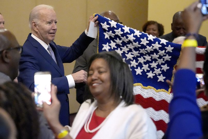 Prezydent Joe Biden trzyma ręcznie wykonaną flagę podarowaną przez kibica.