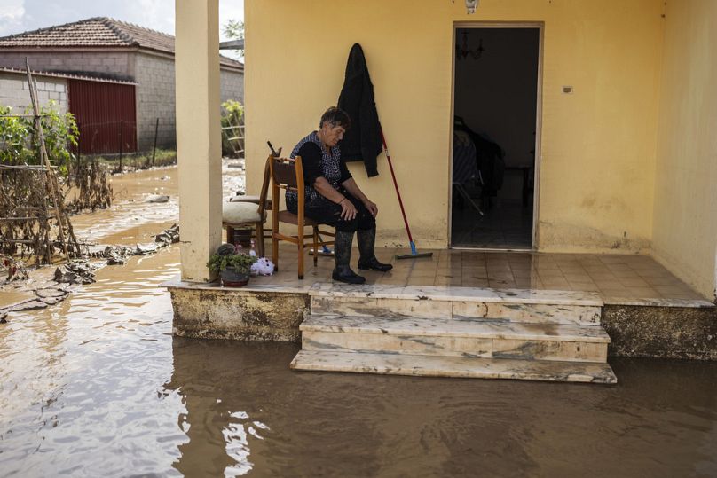 Kobieta robi sobie przerwę w sprzątaniu zalanego domu w wiosce Sotirio niedaleko miasta Volos w Grecji, piątek, 29 września 2023 r.