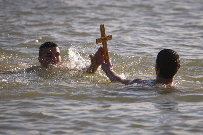 Pływacy trzymają drewniany krzyż wyłowiony z Dunaju podczas obchodów Trzech Króli w Facaieni we wschodniej Rumunii, 6 stycznia 2024 r.