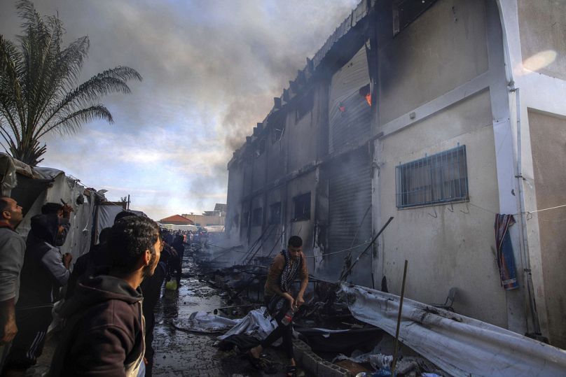 Palestyńczycy próbują ugasić pożar w budynku ośrodka szkolenia zawodowego UNRWA, który służy wysiedleńcom za schronienie po tym, jak najechali na cel izraelskiego czołgu