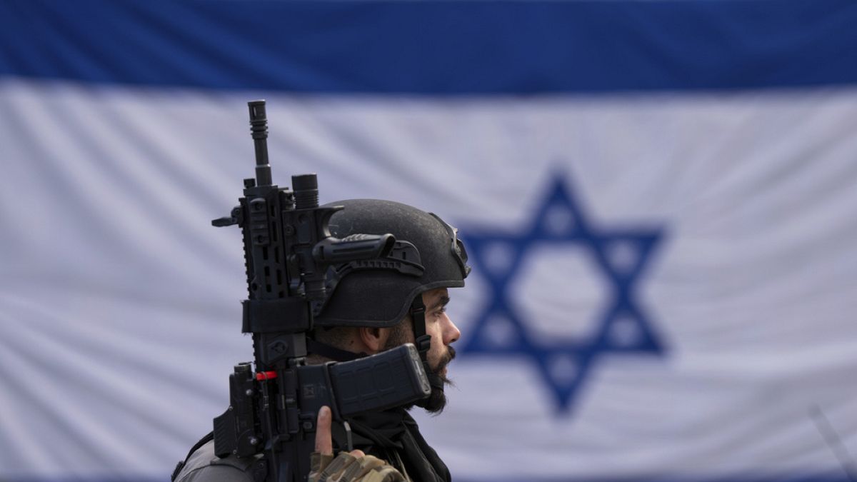 An Israeli border police officer stands guard at  a bus stop in Ra