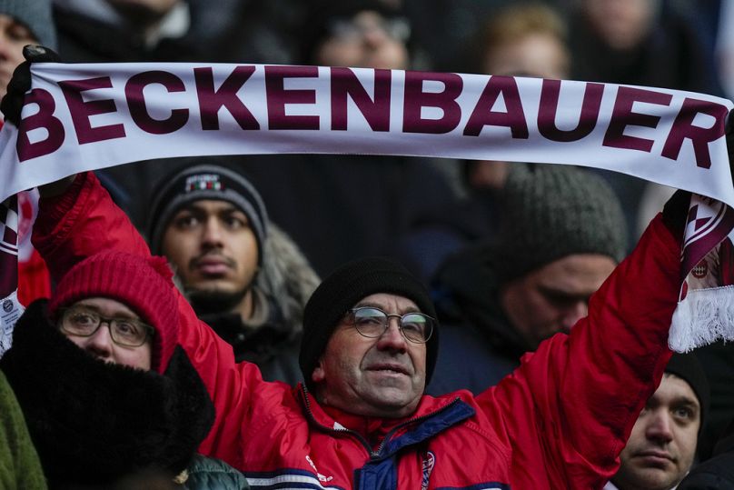 Mężczyzna trzyma szalik podczas nabożeństwa żałobnego dla legendy Bayernu i Niemiec Franza Beckenbauera w Allianz Arena w Monachium, Niemcy, piątek, 19 stycznia 2024 r.